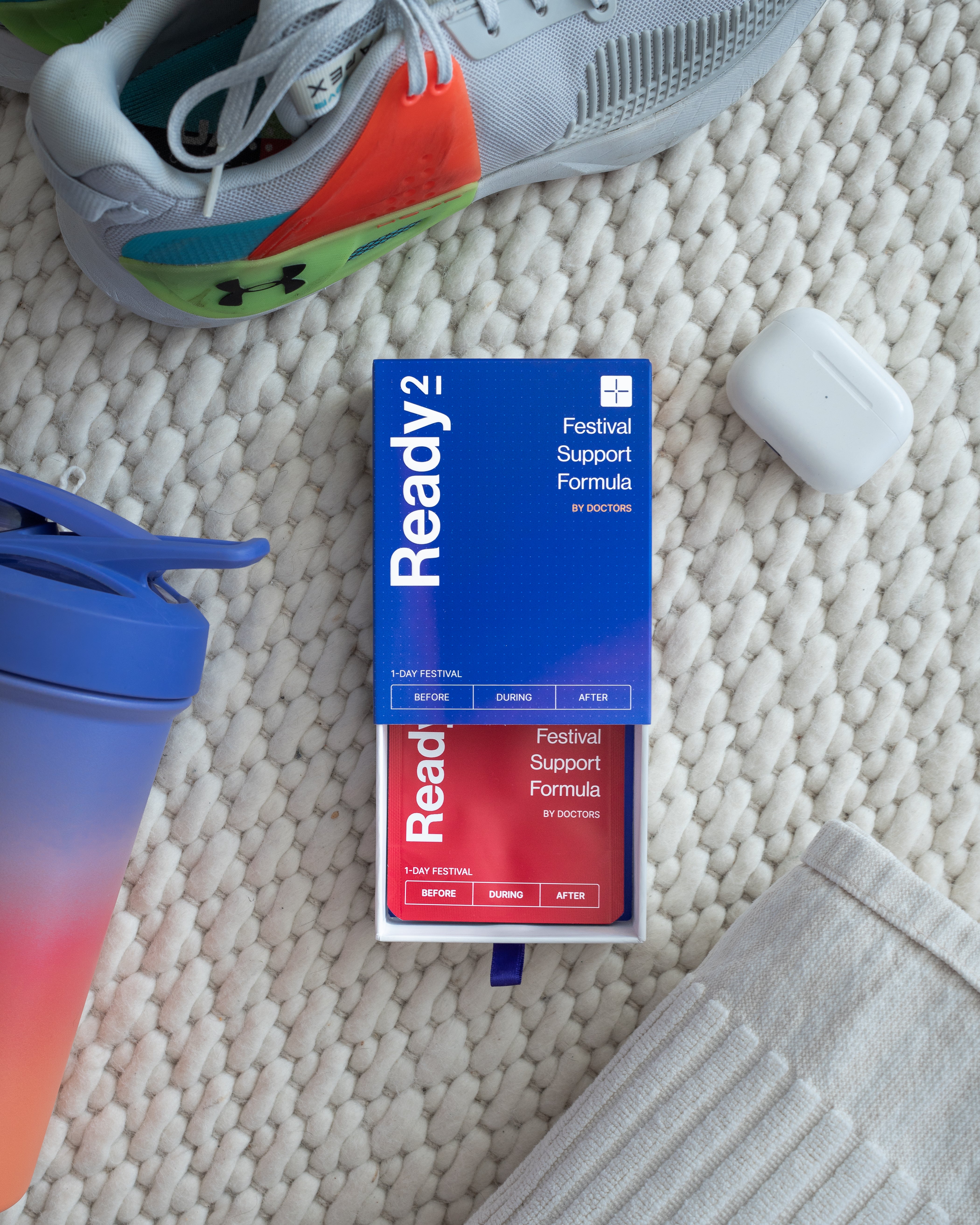 a reviewer making a picture of ready2 package next to daily needs like a gym bottle sneakers and airpods